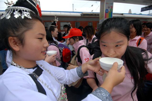 A local girl serves wine to greet college volunteers in Guiyang Railway Station, Guiyang, capital of southwest China's Guizhou Province. Photo: Xinhua